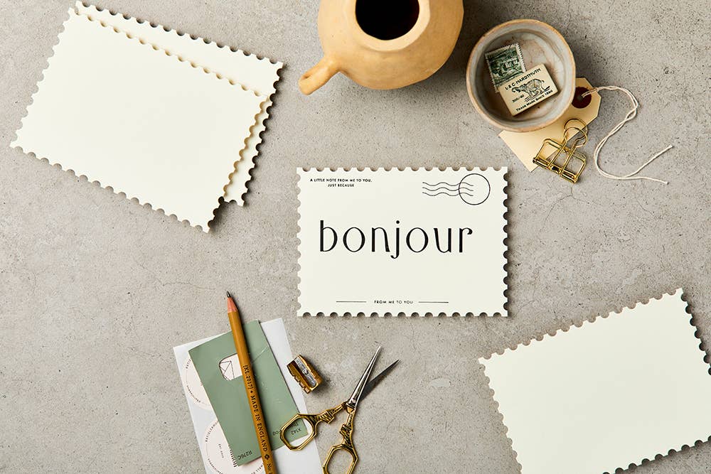 Assorted Notecards, ivory cardstock with scalloped edges, featuring 'bonjour' design, flat lay with desk stationery.