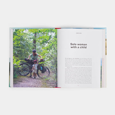 
                    
                      Women Travel Solo book, open to chapter 'Solo woman with a child' featuring a forest biking photo and text.
                    
                  