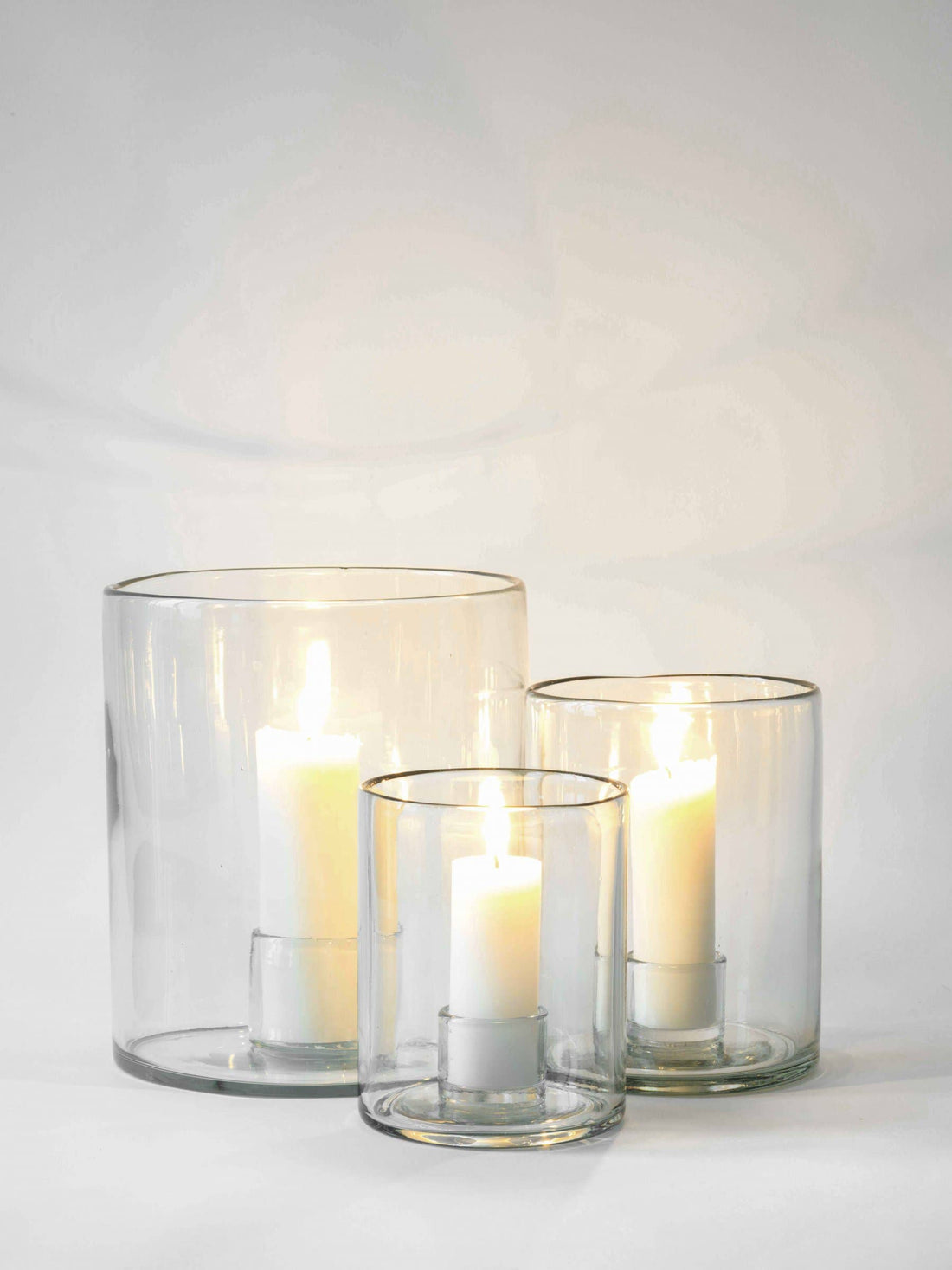 Luna small recycled glass candle holder, shown with two larger Luna glass candle holders, all holding lit white candles.