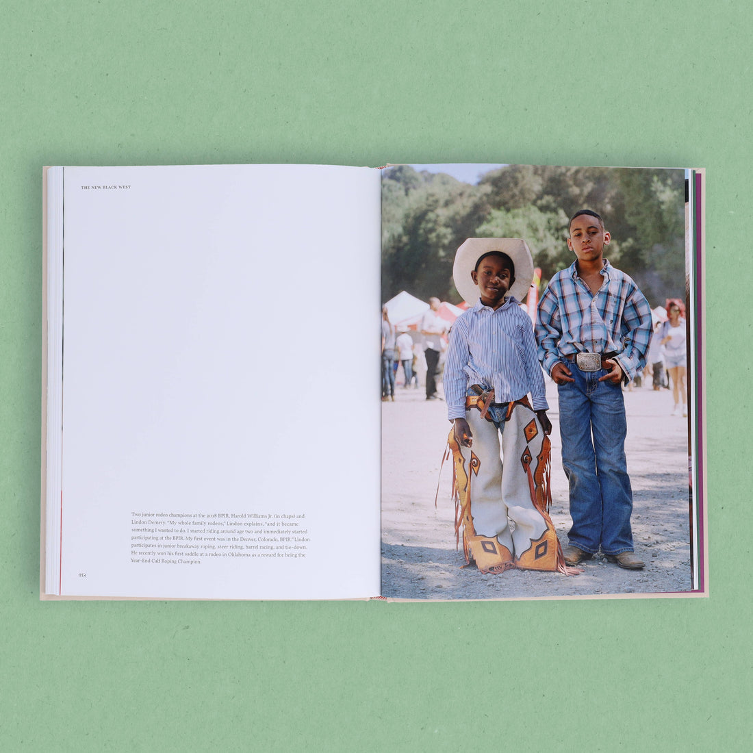 The New Black West book, open showing interior text and a full-color photo of two young Black boys in rodeo chaps, plaid…