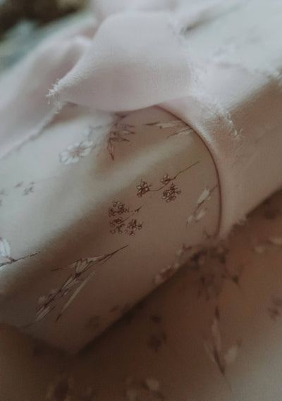 
                    
                      Vintage Blooms wrapping paper, delicate brown botanical illustrations on pale paper, detail view of a rolled edge.
                    
                  