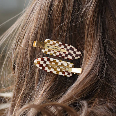 
                    
                      Checkerboard Hair Clips (set of 2), brown, olive, and cream plant-based acetate pattern, clipped into long brunette hair…
                    
                  