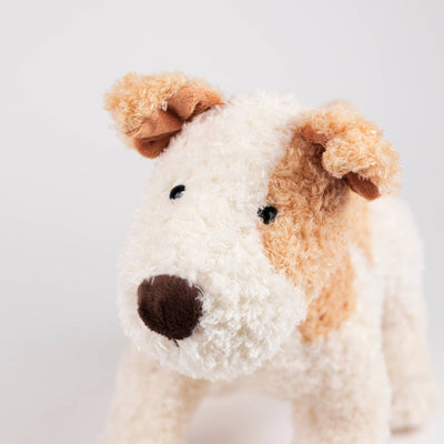 
                    
                      Eliot plush stuffed dog, white and tan curly plush with dark brown nose, close-up angled view of head and shoulders.
                    
                  