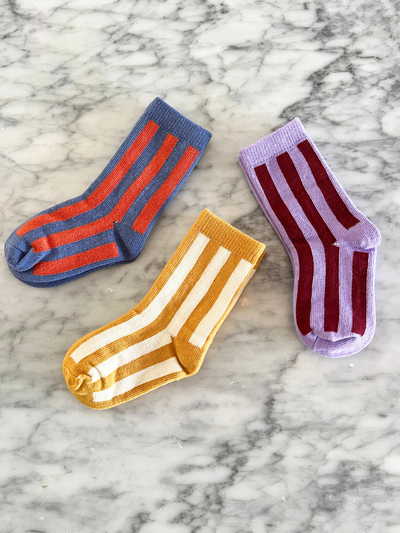 
                    
                      Kids Stripe Socks, cotton knit, in blue with orange, yellow with white, and lilac with maroon stripes, laid flat on marble.
                    
                  