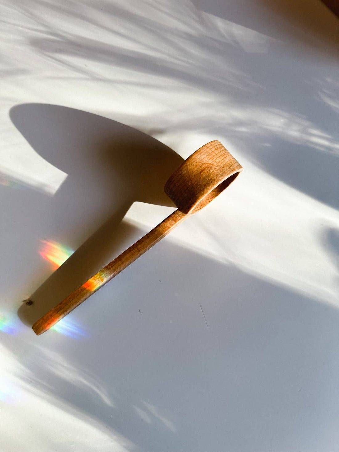 Wooden Tea Scoop, unfinished beechwood, angled close-up view capturing rainbow light prisms