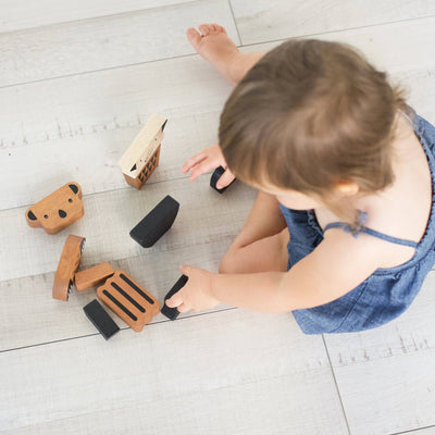 
                    
                      Animal Stacking Tower, natural rubberwood blocks with black details, toddler playing with toy pieces on a light wood floor.
                    
                  