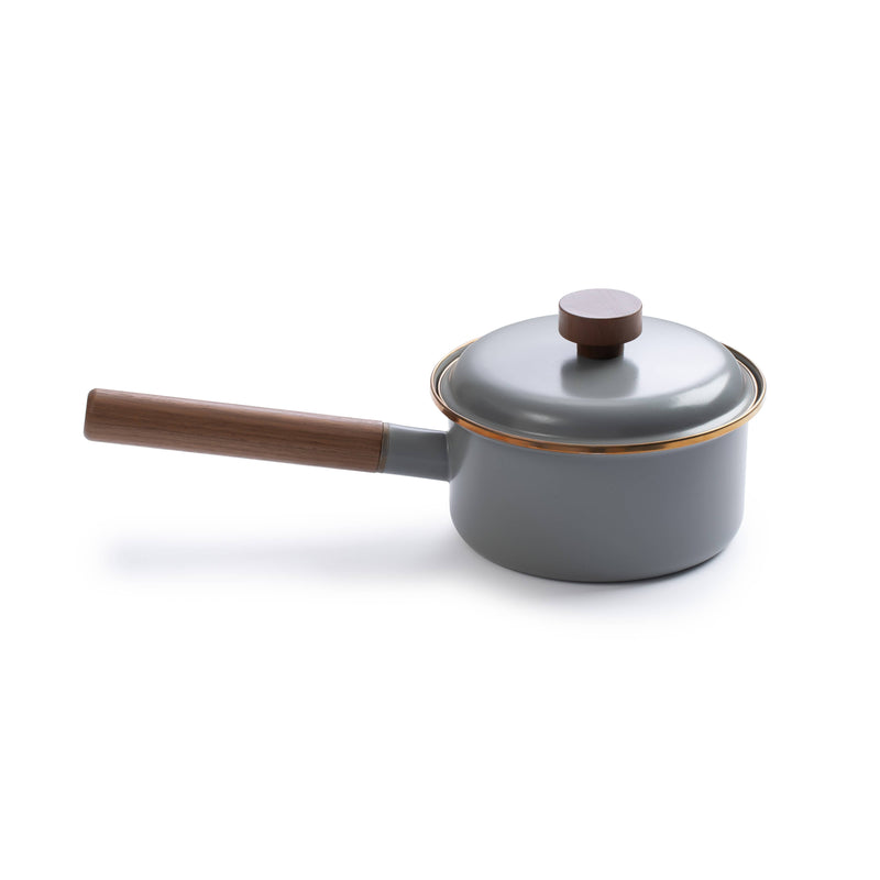 Barebones Enamel Saucepan with Walnut Handle, gray enamel with gold trim, angled view on white background.