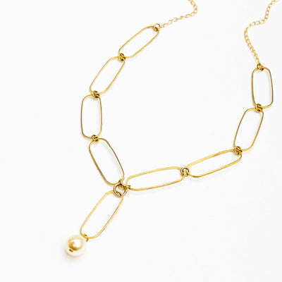 
                    
                      Paperclip And Pearl necklace, matte gold-plated chain with single crystal pearl drop, flat lay on white.
                    
                  