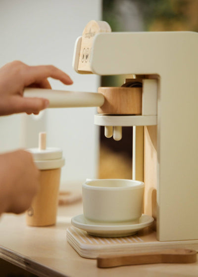 
                    
                      Wooden Coffee Maker Set, close-up of child's hand inserting natural pine portafilter into cream play machine.
                    
                  