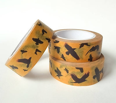
                    
                      Flying Crows washi tape, yellow with black crow silhouettes, three rolls stacked with one leaning, angled view.
                    
                  