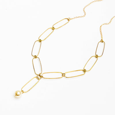 
                    
                      Paperclip And Pearl necklace, gold-plated paperclip chain forms a Y-drop, with a single cream pearl pendant, flat lay.
                    
                  