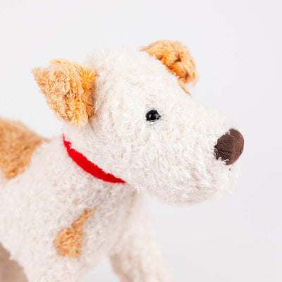 
                    
                      Plush Pull-Along Eliot Dog toy, white polyester plush with light brown patches, close-up profile view of head with red…
                    
                  
