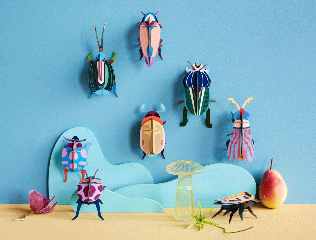 Vibrant 3D model beetle kits, multicolored with striped and spotted designs from recycled cardboard, displayed as a…