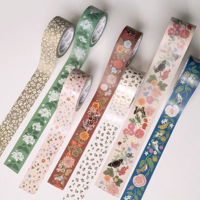 
                    
                      Seven decorative washi tapes unrolled, displaying varied botanical patterns. Russet washi tape features detailed orange,…
                    
                  