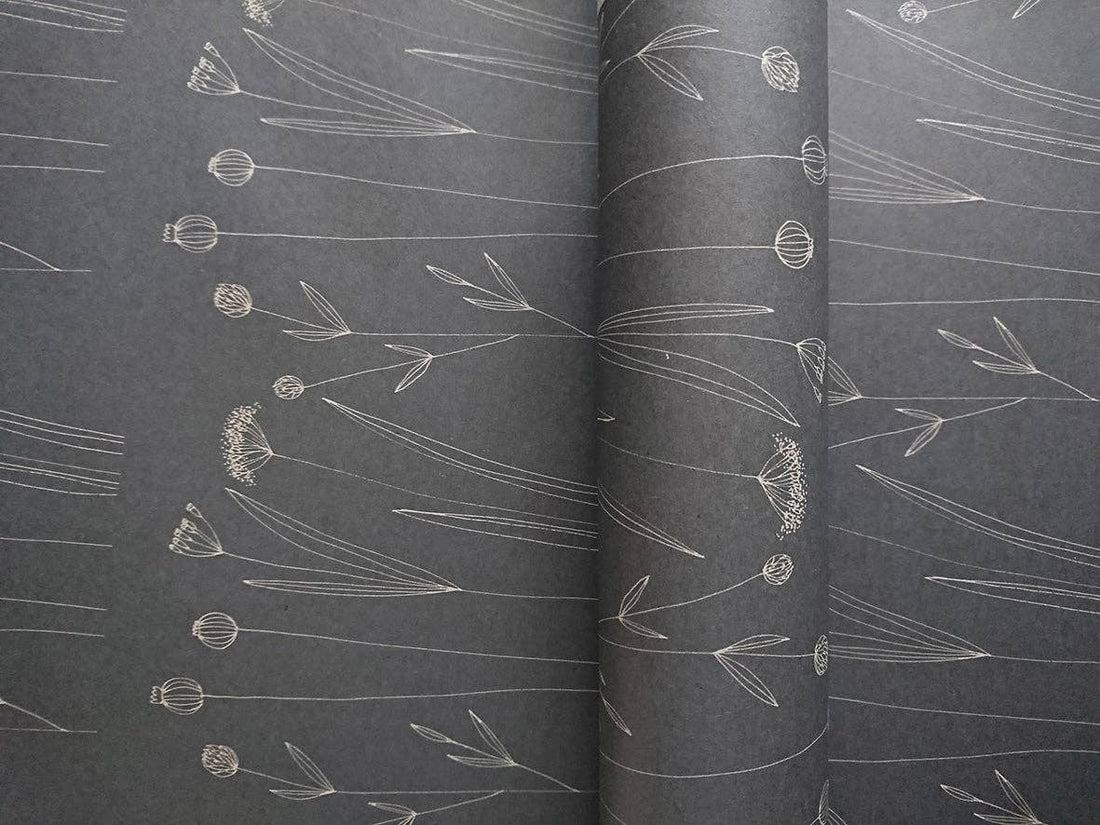 Botanical Wrapping Paper, Agnese Grīnberga's white line art on dark gray recycled kraft paper, close-up of partially…
