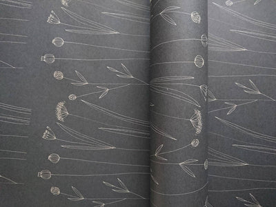 
                    
                      Botanical Wrapping Paper, Agnese Grīnberga's white line art on dark gray recycled kraft paper, close-up of partially…
                    
                  