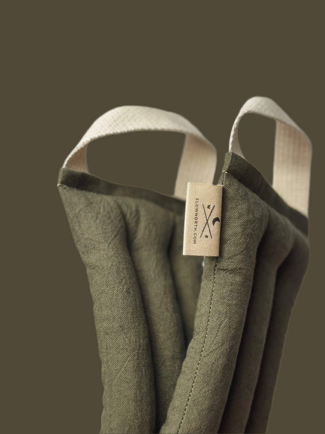 Olive Microwaveable Neck Wrap, cotton linen blend canvas, close-up of fabric texture, quilted channels, and brand label with…