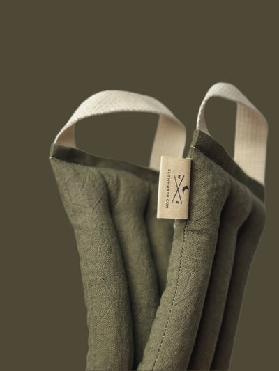 
                    
                      Olive Microwaveable Neck Wrap, cotton linen blend canvas, close-up of fabric texture, quilted channels, and brand label with…
                    
                  