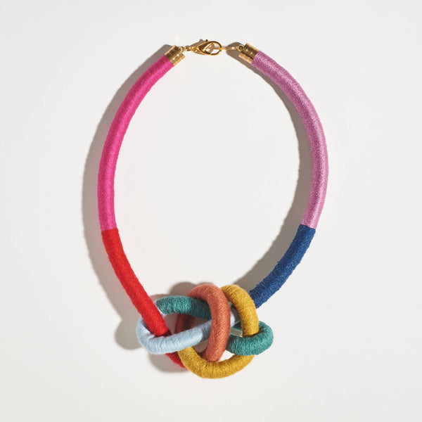 Sasha Water Bowline necklace, rainbow cotton yarn-wrapped cording with a large knot, gold-plated clasp, flat lay on white.