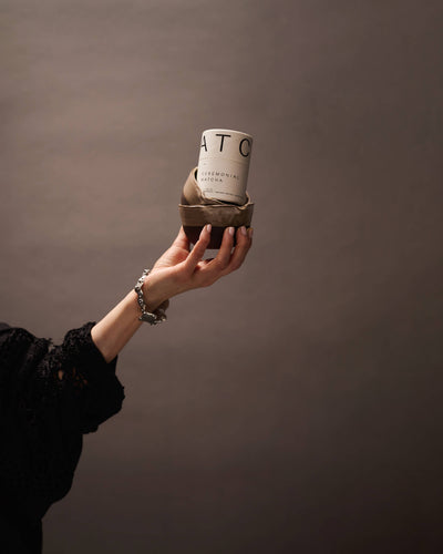 
                    
                      Ceremonial Matcha white tin with black text, sitting in a two-toned brown ceramic bowl, held by a hand for scale.
                    
                  