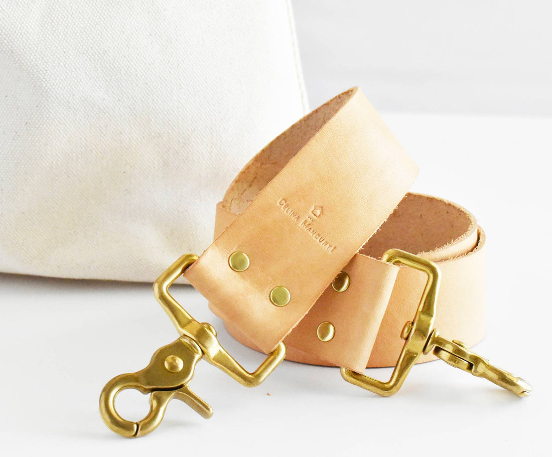 Celina Mancurti Everyday Tote Bag: tan leather strap, close-up detail of brass hardware, rivets, and embossed logo, natural…