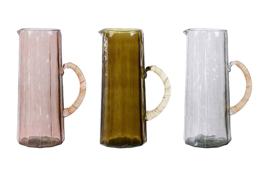 Hammered Glass Pitchers, a trio in rose, olive green, and clear handblown glass with rattan handles, side-by-side.