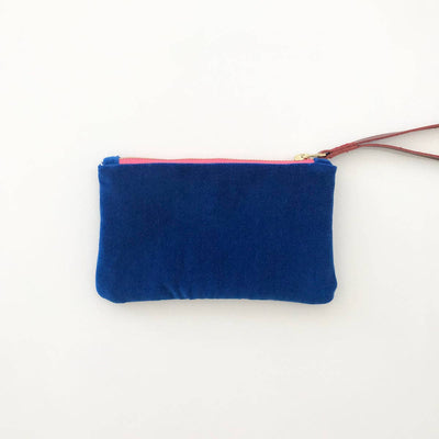 
                    
                      Ellie wristlet in deep blue velvet, showing bright pink zipper with brass pull and brown leather strap, flat lay front view.
                    
                  