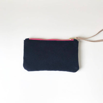 
                    
                      Ellie wristlet in black cotton velvet, with bright pink zipper, brass pull, and tan leather strap, flat lay.
                    
                  