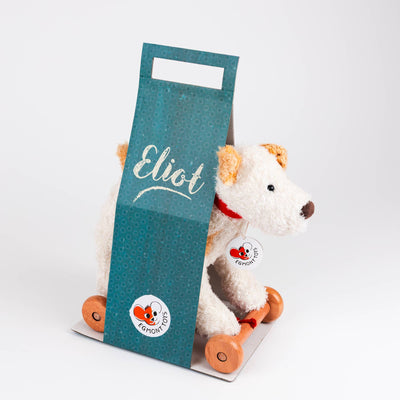 
                    
                      Plush Pull-Along Eliot Dog, white and tan plush with red collar, peeking from teal packaging with 'Eliot' script, solid wood…
                    
                  