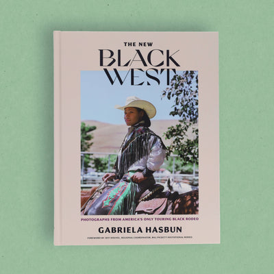 
                    
                      The New Black West book, full front cover featuring a cowboy rider, light pink cover, flat lay on green background.
                    
                  