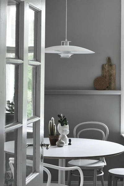 
                    
                      Green Home Book: bright living space with white round table, chairs, potted cactus, plants. Scene viewed through open door.
                    
                  