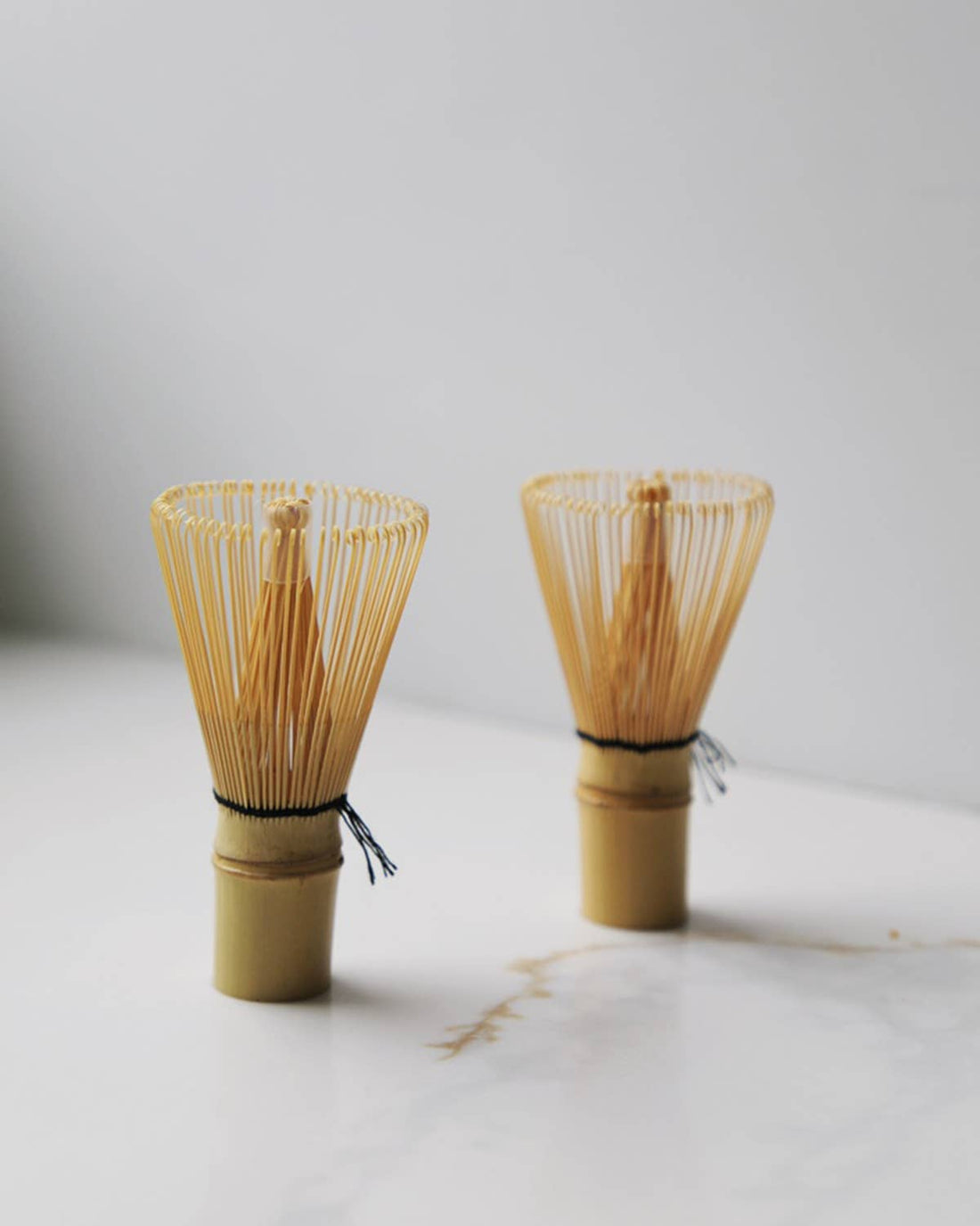 Fodory Japanese Style Chasen bamboo tea whisks, natural bamboo with black string detail, pair front view on white surface.