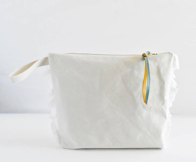 
                    
                      Ruffle Cotton Zipper Pouch, natural cotton, detailed view of side ruffles, gold zipper, and yellow/blue leather pull.
                    
                  