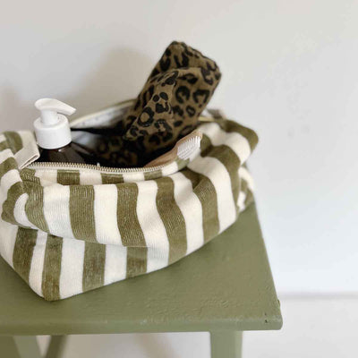 
                    
                      Vic toiletry bag, Terry Olive 100% cotton terry with olive green and white stripes, open top showcasing interior with pump…
                    
                  