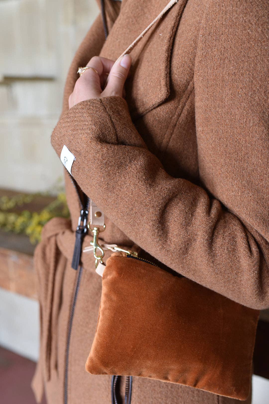 Erin Flett Ellie Wristlet, caramel velvet, close-up of brass hardware and leather attachment on a brown coat.