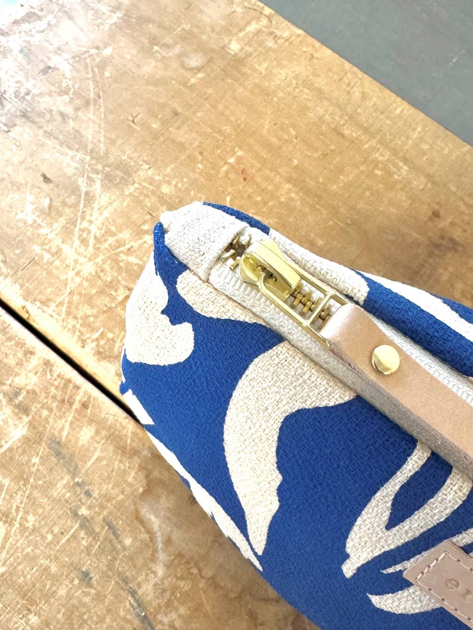 Laura Pouch cosmetic pouch, close-up of brass zipper and natural leather pull on blue and white tulip pattern barkcloth.