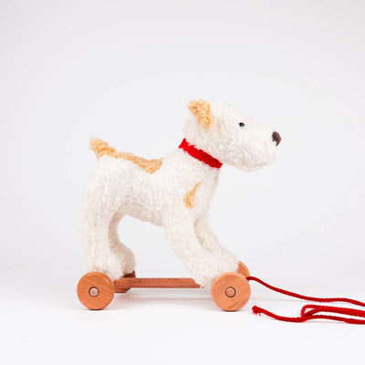 
                    
                      Egmont Eliot pull-along toy, cream plush dog with tan patches, red collar, natural wood wheels, side view showing red pull…
                    
                  