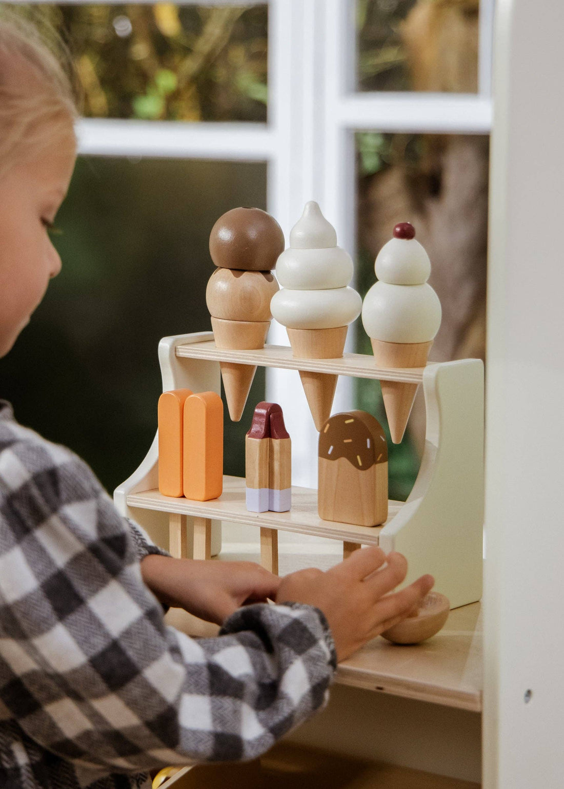Wooden Ice Cream Stand play food set, child's hands arranging natural wood & colorful painted ice cream treats.