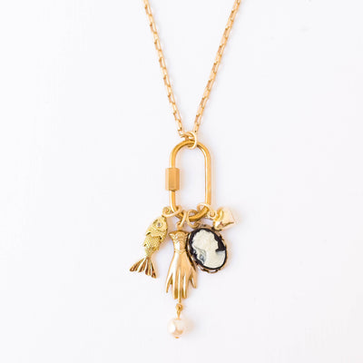 
                    
                      Nest Pretty Things Gold Carabiner Charm Necklace. Gold-plated chain, carabiner, cameo, crystal fish, hand, heart, and pearl…
                    
                  