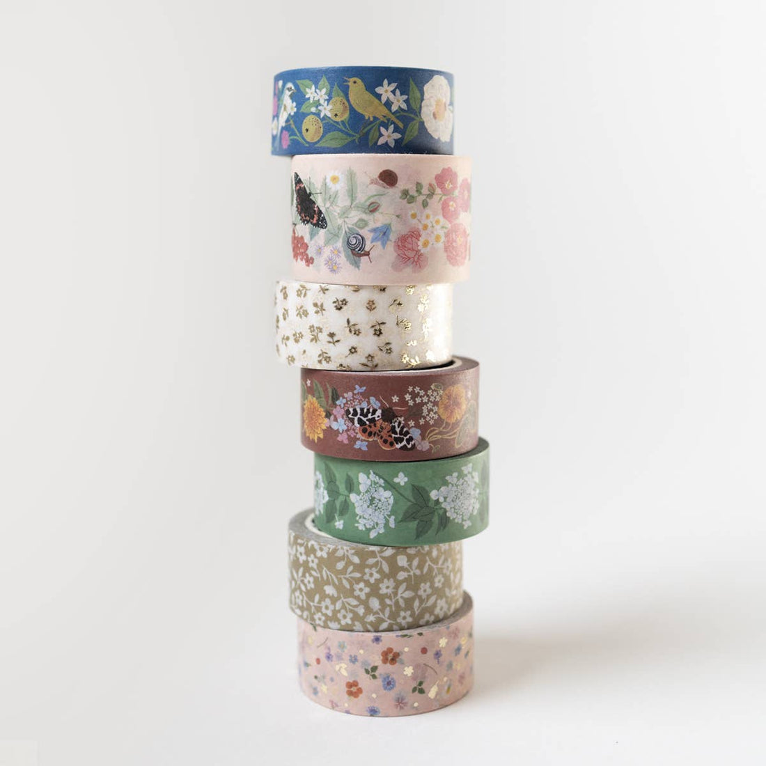 Song Birds washi tape, a stack of seven rolls, each featuring unique floral, bird, and butterfly patterns with gold foil…