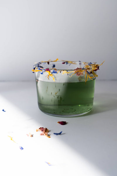 
                    
                      Flower Sprinkles edible decor, organic blue, yellow, and reddish flower petals garnishing the rim of a green drink in a…
                    
                  