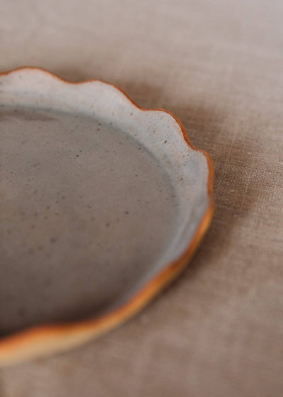 
                    
                      Handcrafted Stoneware Plate, gray with natural speckles, featuring a distinct wavy scalloped rim in warm terracotta orange,…
                    
                  