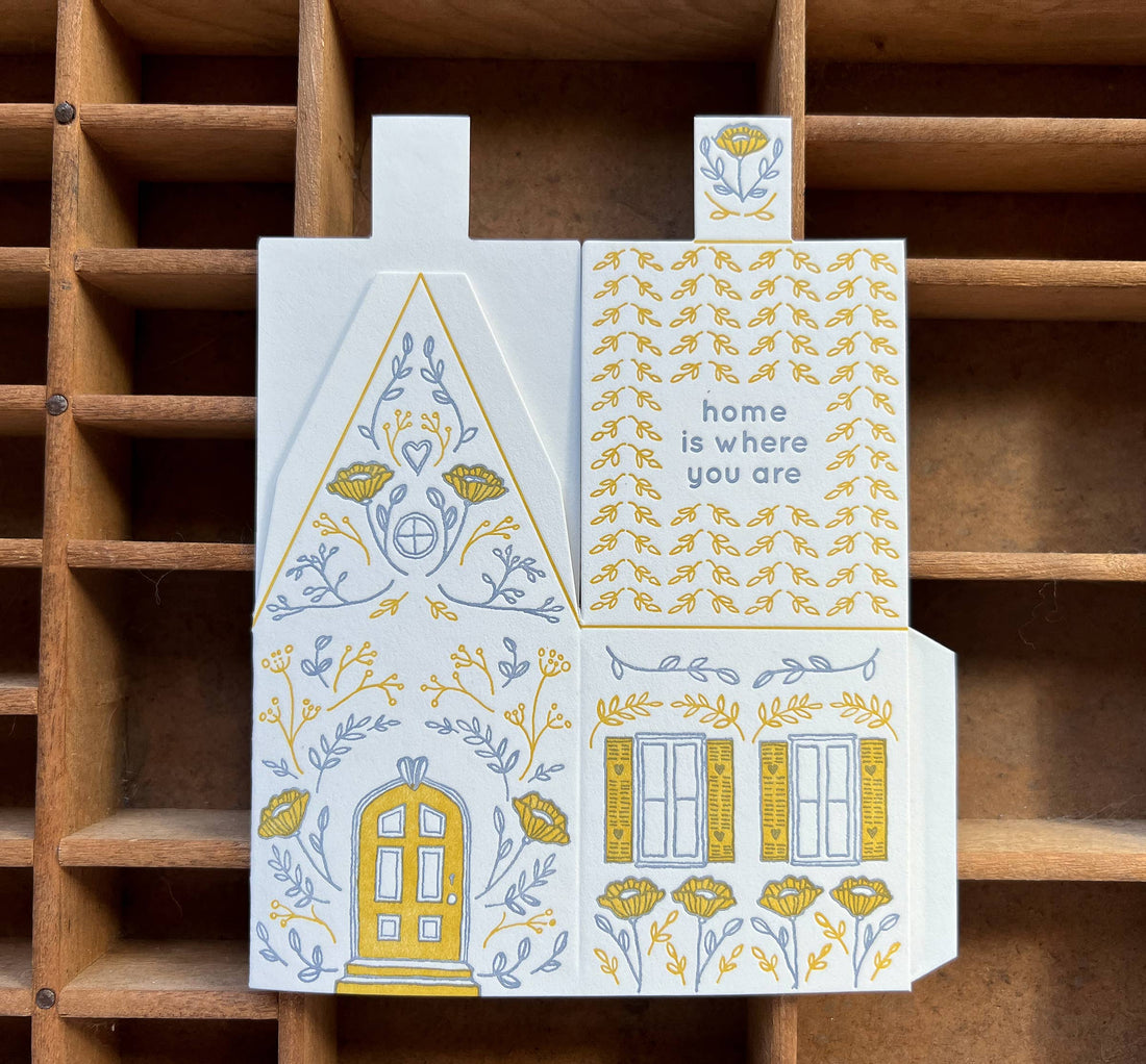 Home Is Where You Are 3D die-cut greeting card, unfolded, featuring yellow & grey letterpress house illustration with door,…