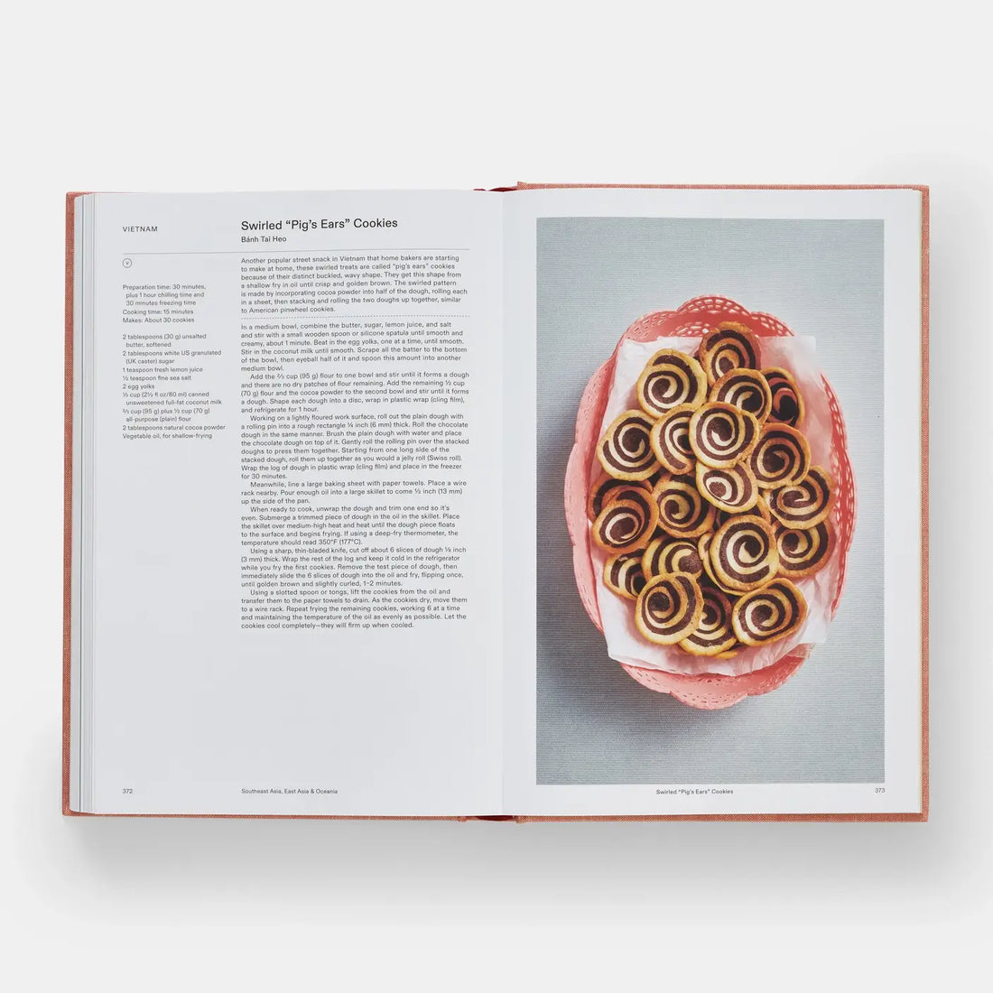 Crumbs cookbook open to 'Swirled Pig's Ears Cookies' recipe, showing brown and white swirl cookies in a pink basket.