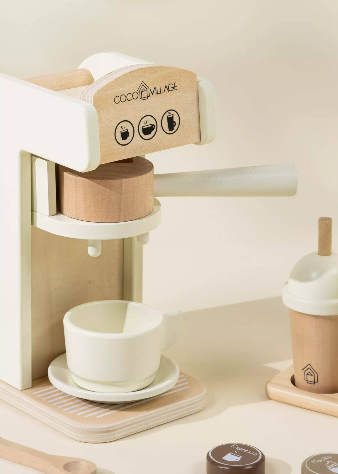 Wooden Coffee Maker play set, natural wood & cream, close-up with handle pulled, cup & saucer ready, and pods nearby.