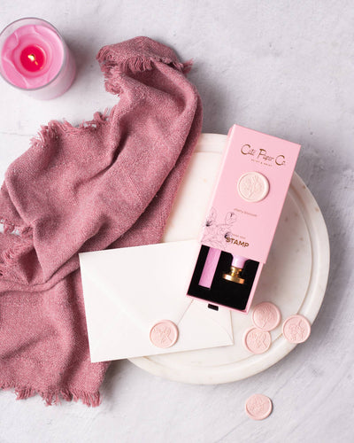 
                    
                      Cate Paper Co. Cherry Blossom Wax Seal Stamp, open pink box, gold handle, pink wax seals on white envelope, flat lay.
                    
                  