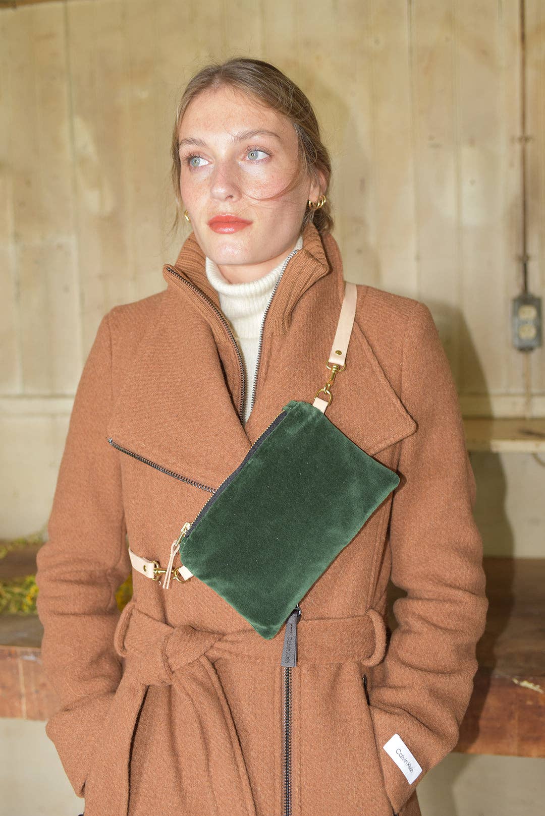 Erin Flett Velvet Ellie Wristlet, dark green velvet with natural leather strap and brass hardware, worn cross-body on model.