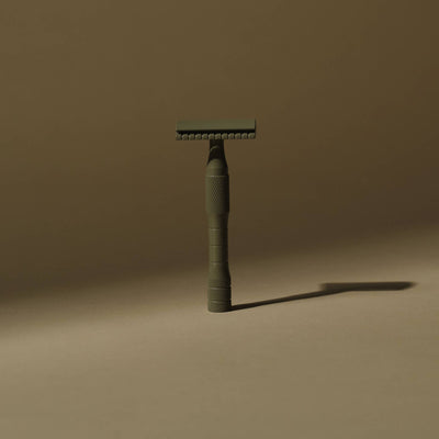 
                    
                      Kelp safety razor, standing upright, showing Kelp green brass and textured knurled handle detail.
                    
                  