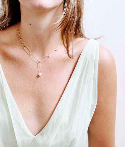 
                    
                      Nest Pretty Things Paperclip And Pearl necklace, gold paperclip chain with single pearl drop, on model décolletage.
                    
                  