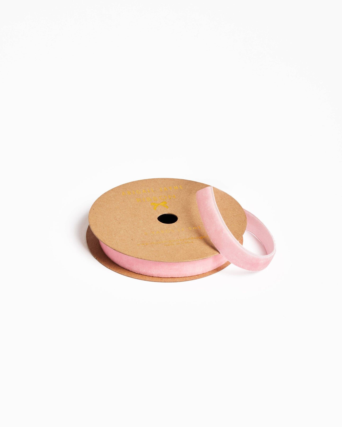 Spool of pink ribbon on a cardboard reel with a white background